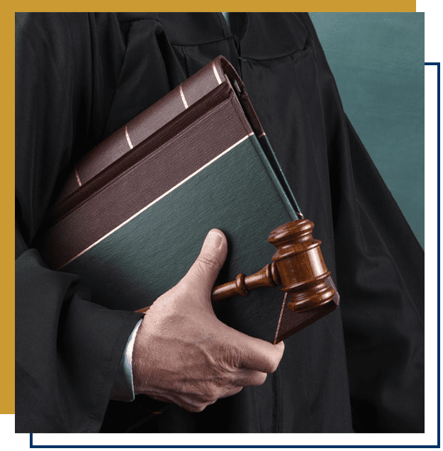 A close-up of a court judge in a court robe holding a book and a gavel.